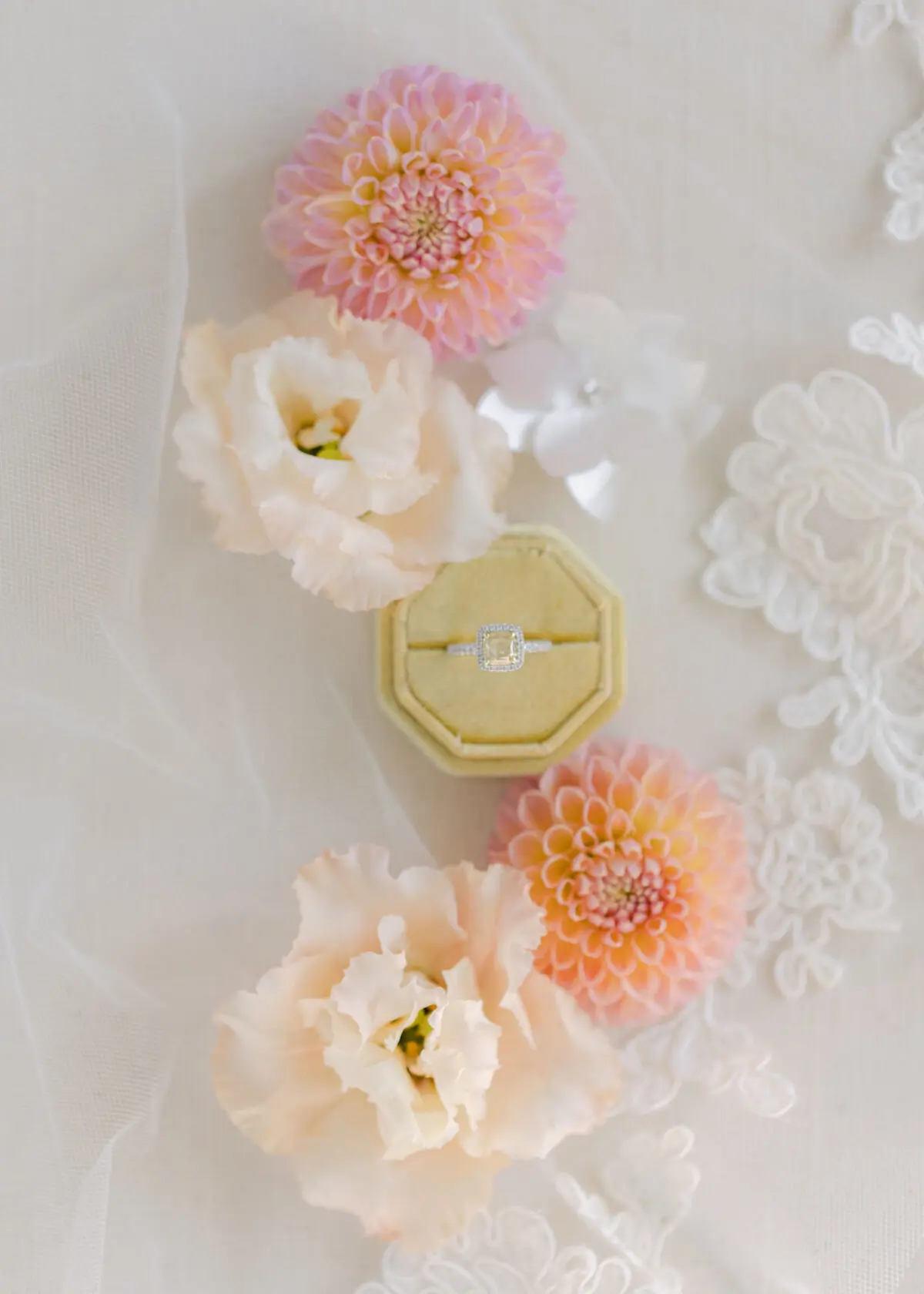 flat lay of engagement ring in yellow ring box surrounded by flowers on lace veil - buckinghamshire wedding
