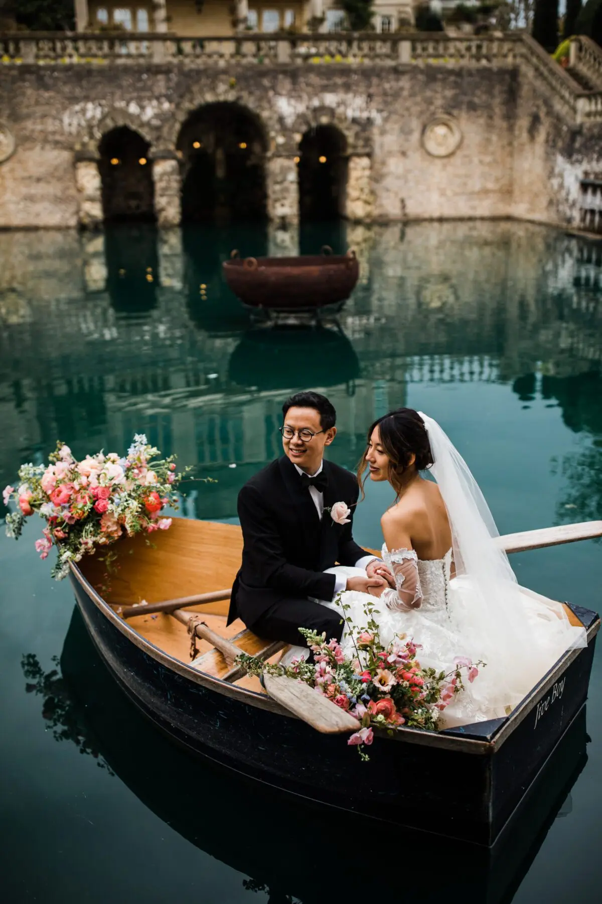 Bride and groom in boat dressed in flowers in lake - wedding designer