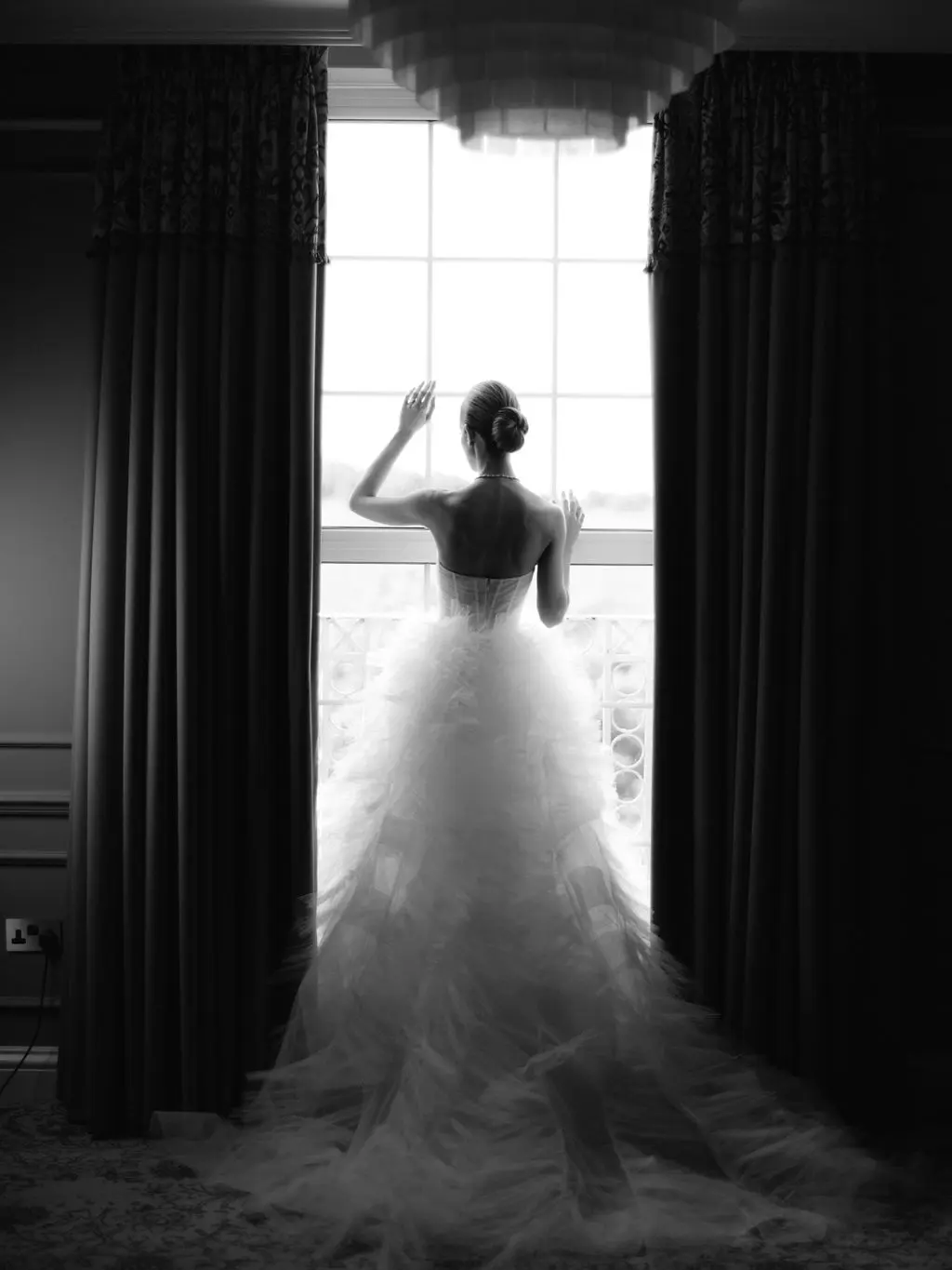 Black and white image of bride looking out window at Four Seasons Hampshire