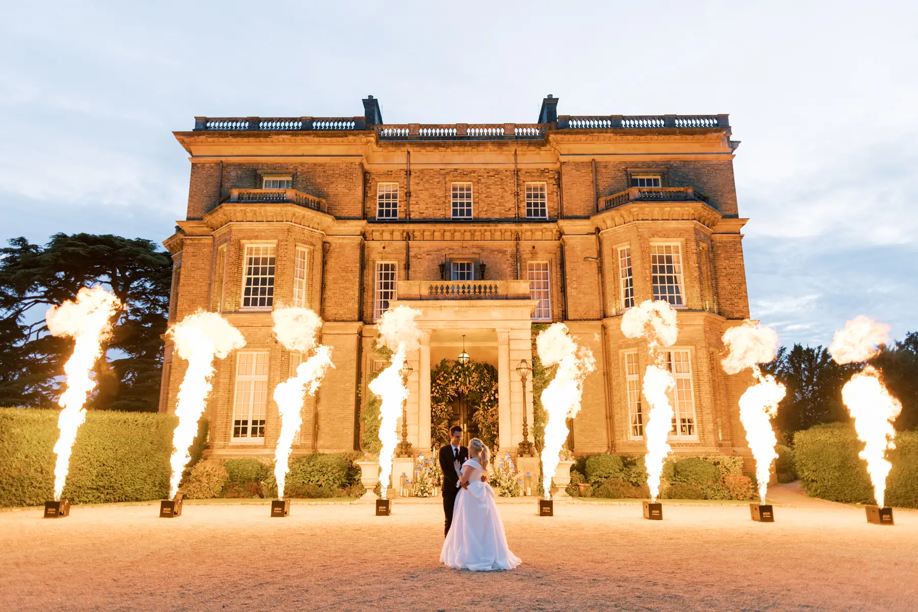 Bride and groom infront of Hedsor House with flames