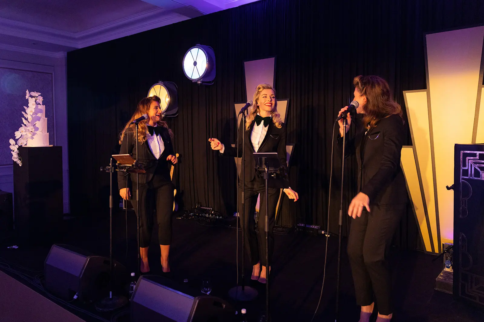 Three girls in black suits singing on stage | Luxury Event Planner