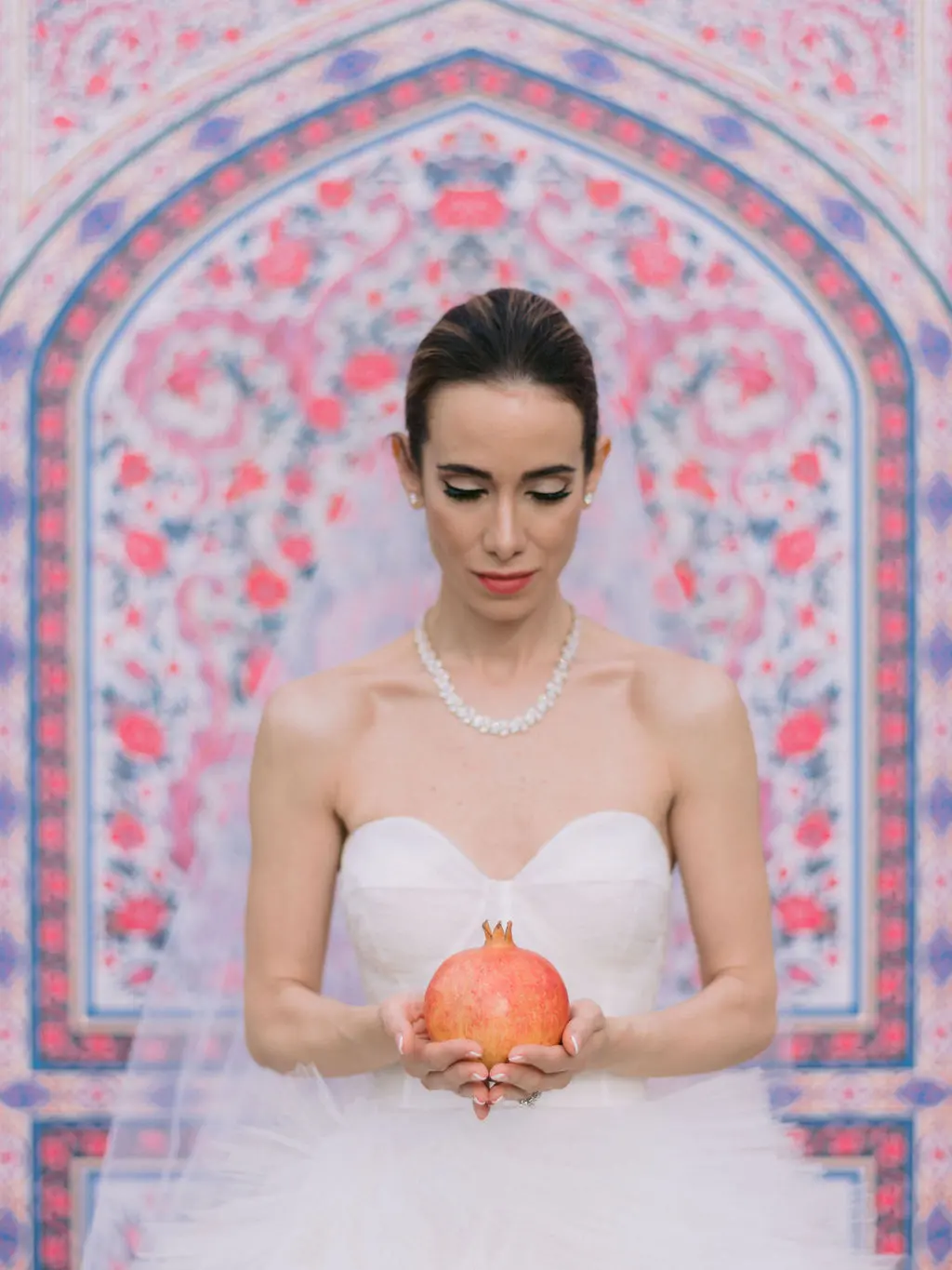 Bride in bespoke oscar de la renta dress holding pomegranate in front of feature ceremony backdrop - Vogue wedding feature