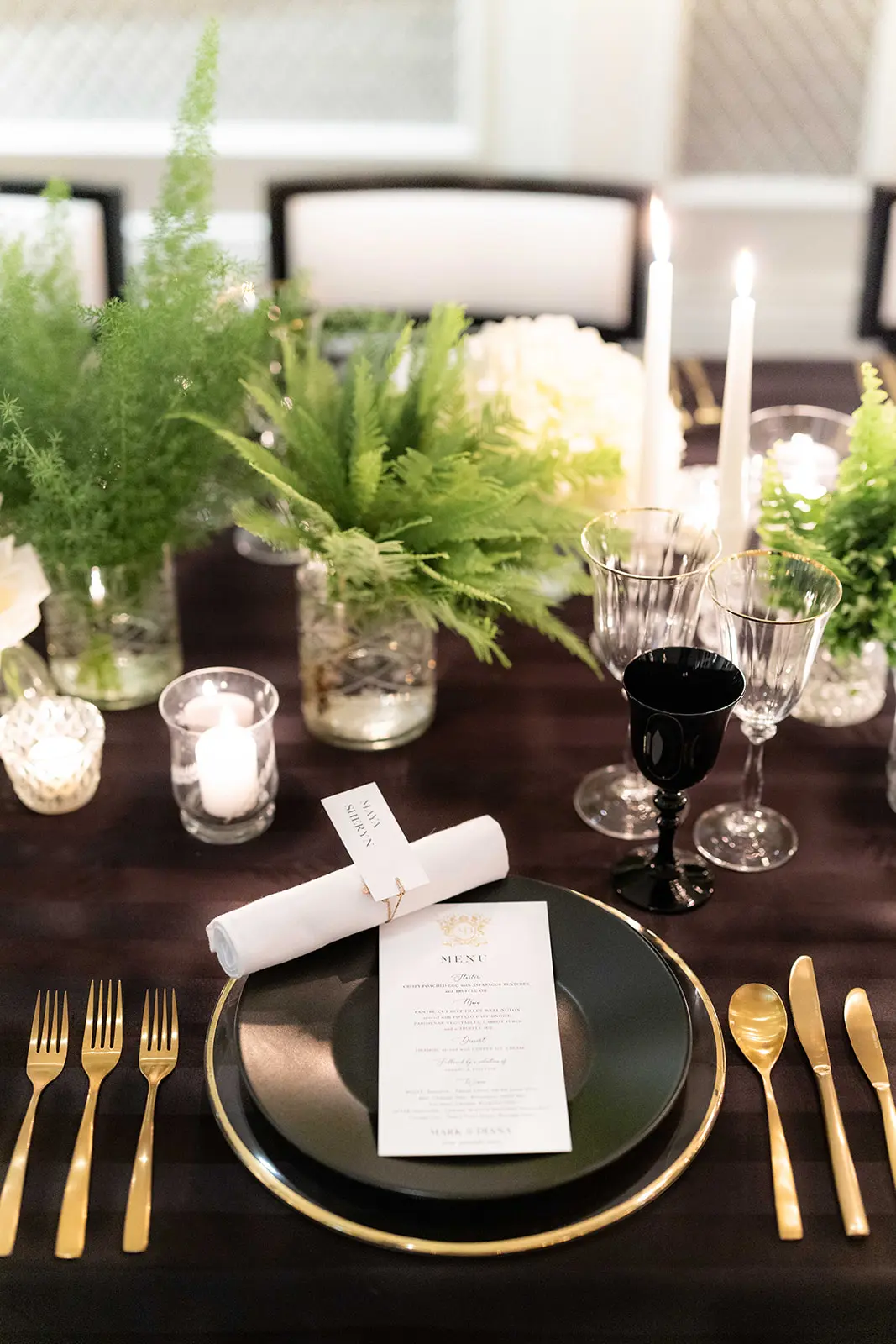 close up image of table design, gold cutlery on black table cloth with white and green flowers - monochrome wedding