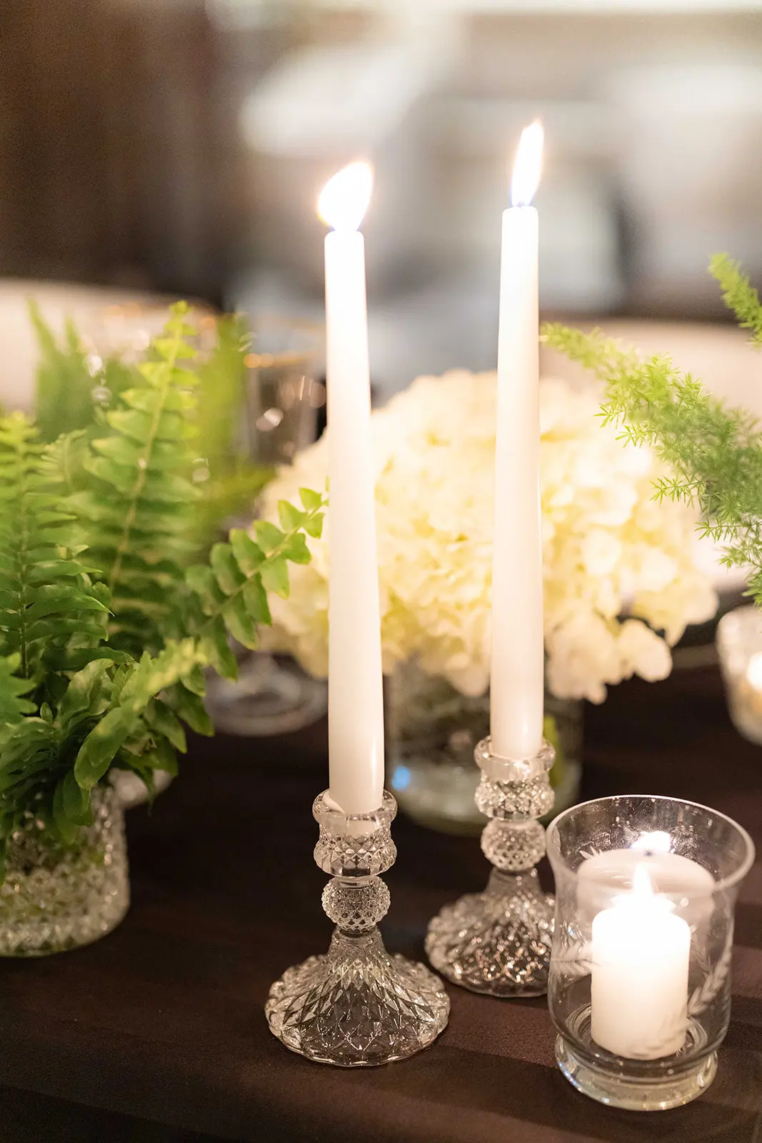 Close up of white tapered candles and white and green flowers