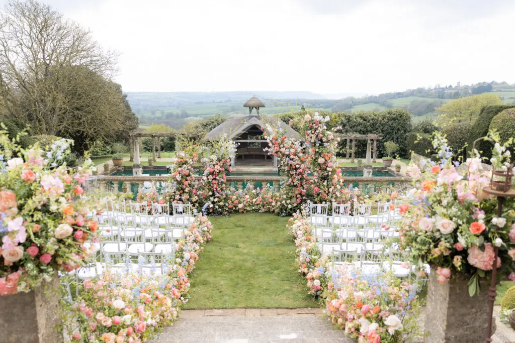 Double floral arch at Euridge Manor in bright spring colour in front of boat house