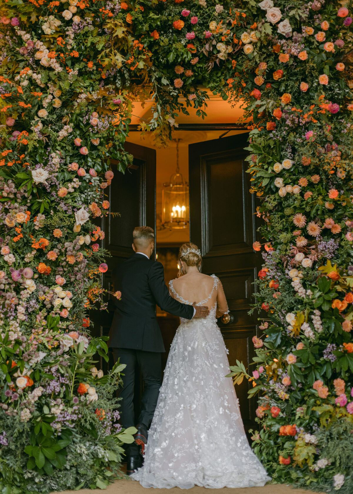 bride and groom walking under large floral arch - Buckinghamshire wedding