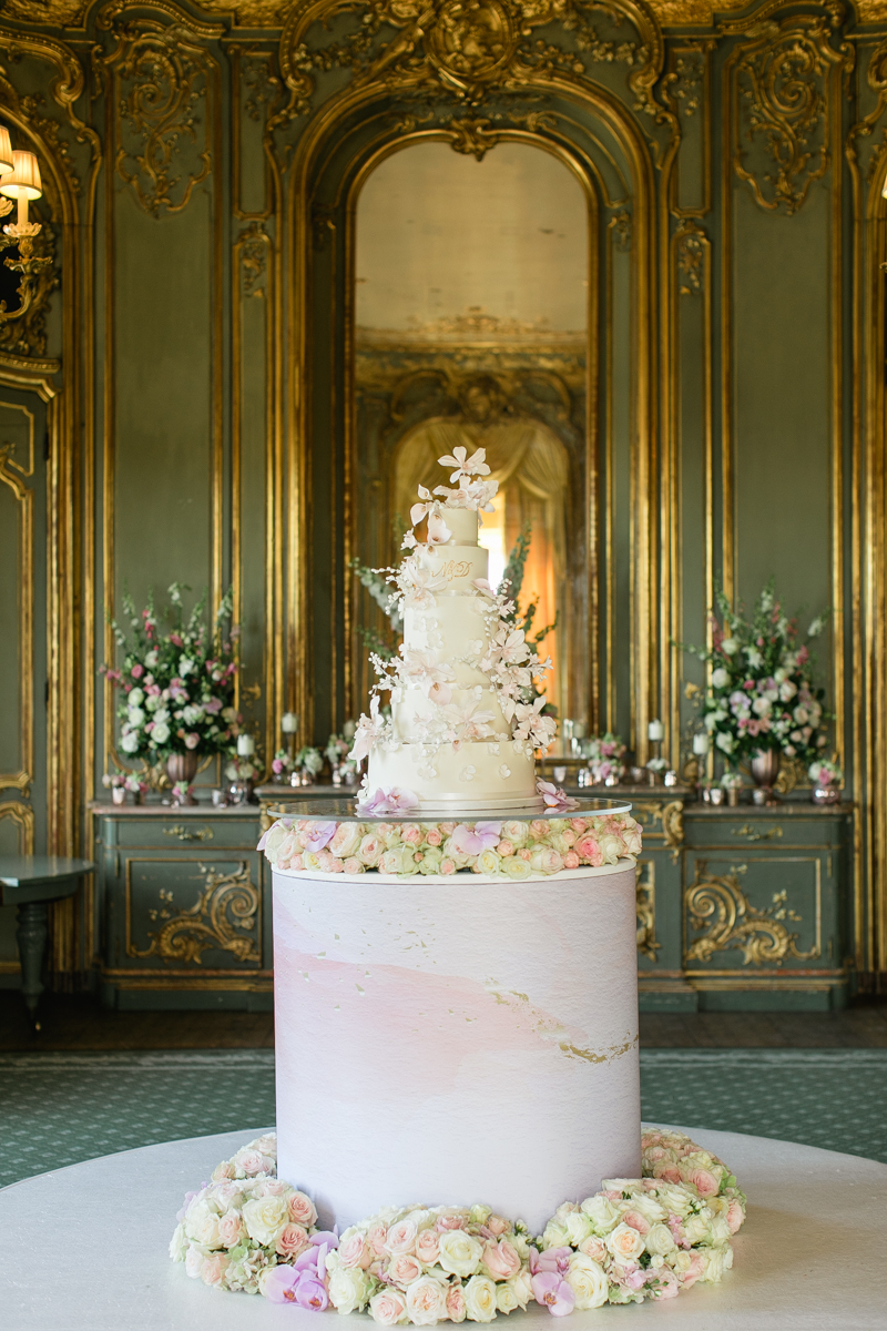 wedding cake on pink marble plinth surrounded in flowers