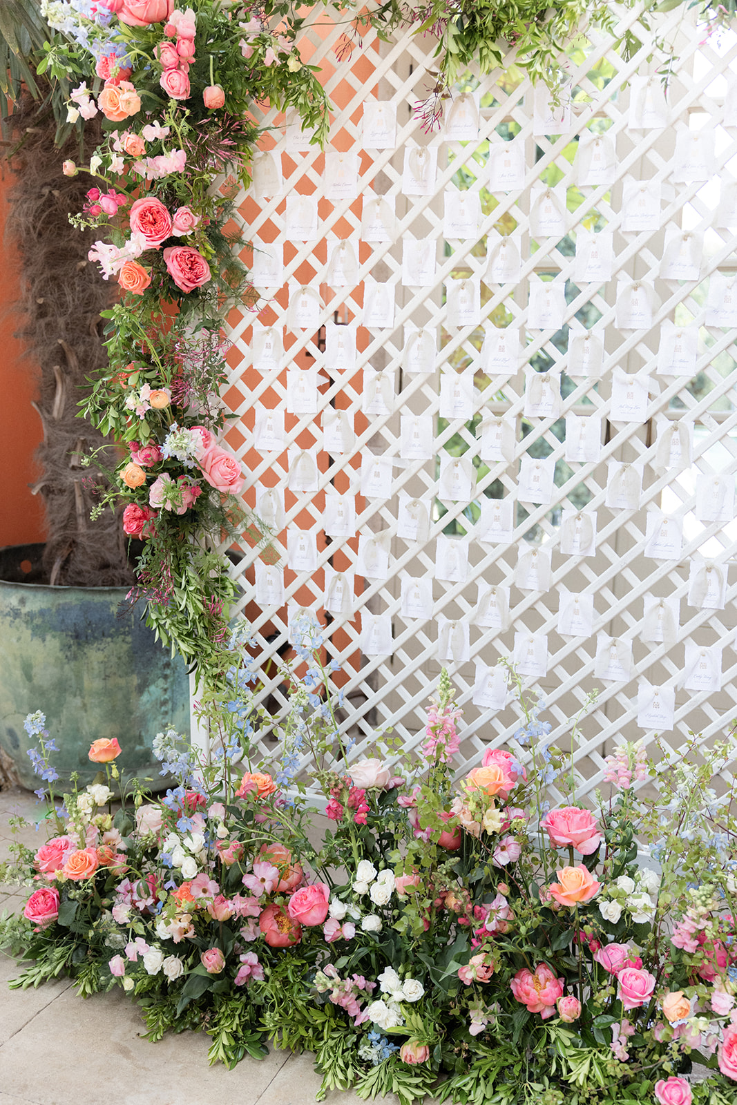 wedding escort card wall on white trellis dressed in flowers - wedding designer