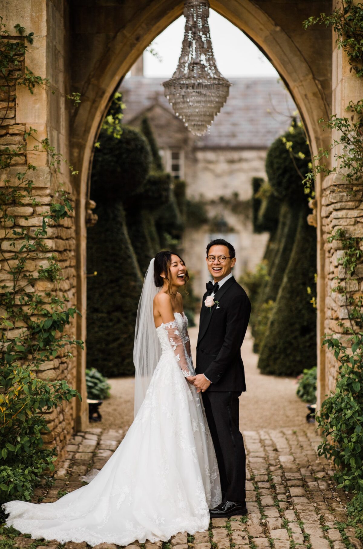 Bride and groom posing under chandelier at Euridge Manor | Wedding designer