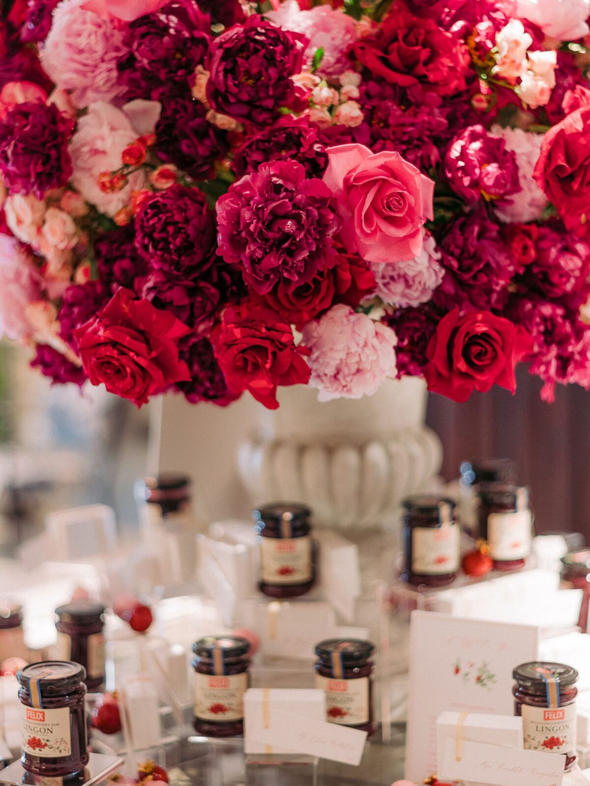 Close up image of large urn of red and pink roses and peonies