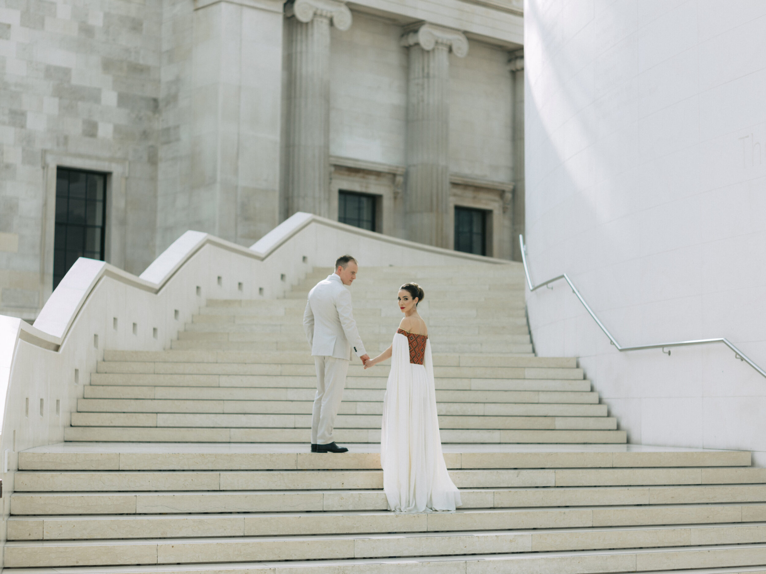 Bride and groom walking up steps at their pre wedding event at the British Museum for this Vogue wedding feature