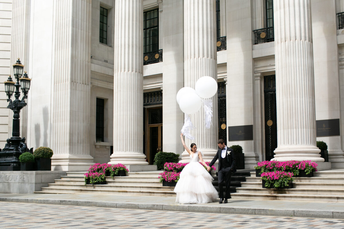 Bride and groom walking down steps of Four Season at Ten Trinity holding giant white balloons